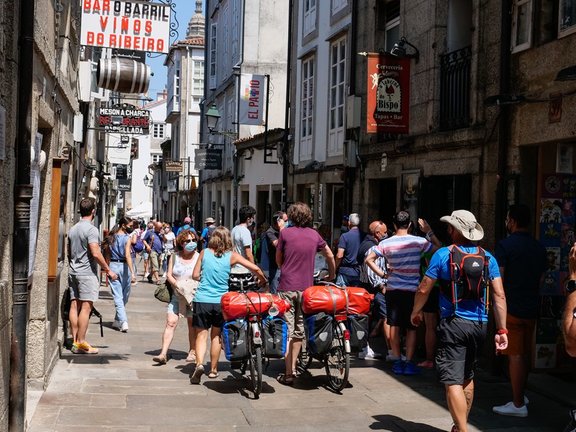 Varios peregrinos caminan con su bicicleta por la Rua do Franco,  en Santiago de Compostela
