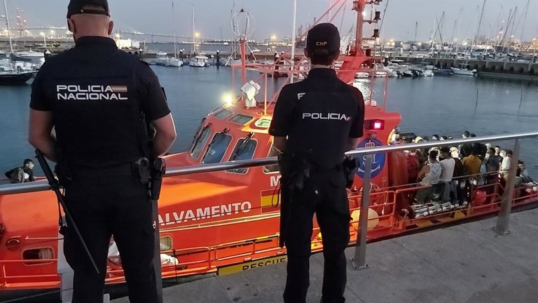 Agentes de la Policía Nacional, junto a la embarcación de Salvamento que rescató a los migrantes de una patera