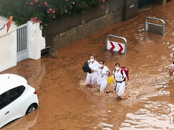Tres sanitarias atraviesan una calle inundada este domingo en Benicàssim (Castellón)
