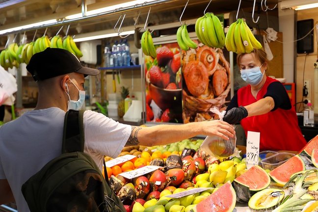 Archivo - Una trabajadora de una frutería del Mercado Central de Valencia atiende a un cliente.