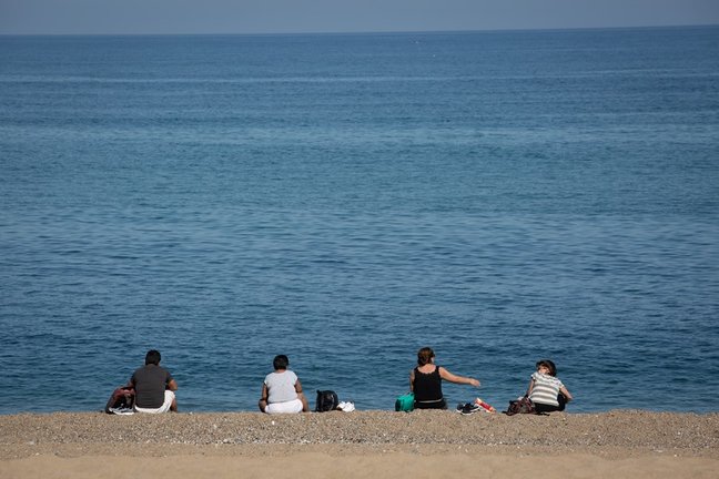Archivo - Varias personas sentadas en la Playa de la Barceloneta de Barcelona