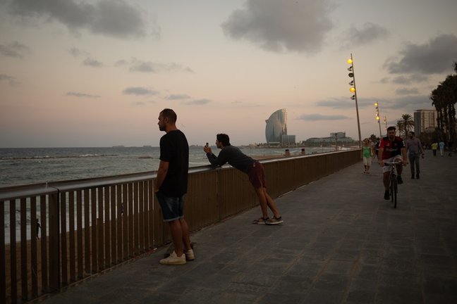 Dos hombres miran el paisaje frente a la playa de la Barceloneta, a 4 de agosto de 2021, en Barcelona, Catalunya (España). 