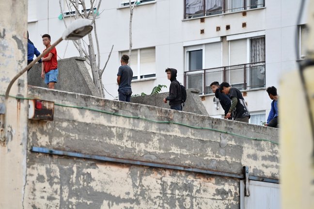 Varios menores migrantes, en el tejado de una nave industrial, a 27 de agosto de 2021, en Ceuta, (España). La Policía Nacional ha desalojado a varios menores que se encontraban en el tejado de esta vieja nave industrial, en la zona portuaria de Ceuta.