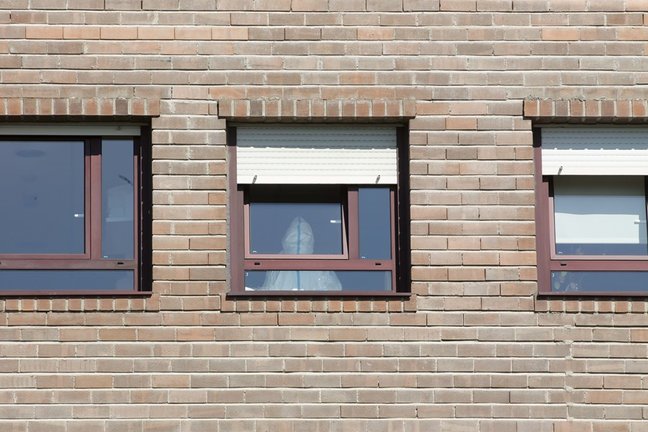 Un trabajador sanitario con un EPI, en la ventana de una habitación de la residencia de Las Gándaras, la mayor de Lugo, después de contabilizar un total de 49 positivos, a 17 de agosto de 2021, en Lugo, Galicia (España). La mayoría de los positivos son as