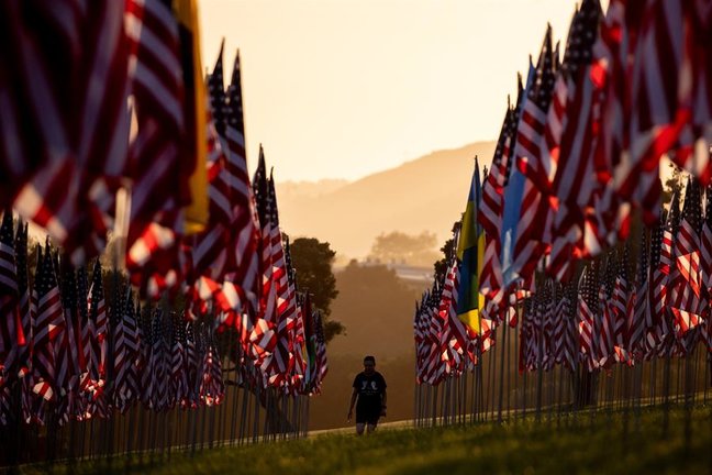 Un visitante camina al atardecer entre las banderas de la instalación conmemorativa "Olas de Banderas" en la víspera del 20º aniversario del 11-S, en la Universidad de Pepperdine en Malibú, California, Estados Unidos, el 10 de septiembre de 2021. La muestra "Olas de banderas" comprende 2977 banderas estadounidenses y extranjeras, en honor a las vidas perdidas en los atentados terroristas de Nueva York, Pensilvania y Washington, D.C. Pepperdine organiza la muestra cada año en septiembre con casi 3.000 banderas en el Alumni Park a lo largo de la Pacific Coast Highway y el Malibu Canyon. (Atentado, Terrorista, Estados Unidos, Nueva York) EFE/EPA/ETIENNE LAURENT