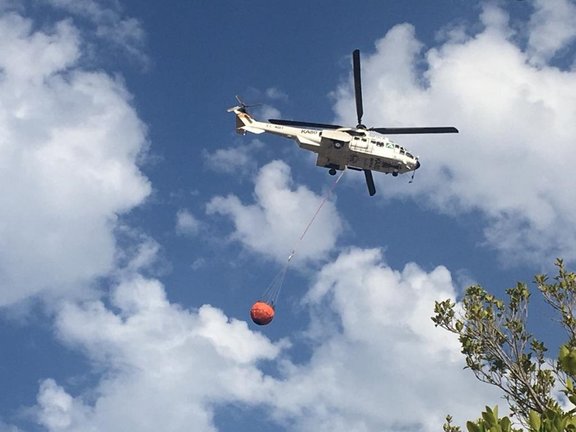Un helicóptero trabaja en la zona del incendio en Sierra Bermeja, al que se incorporan también bomberos de málaga capital