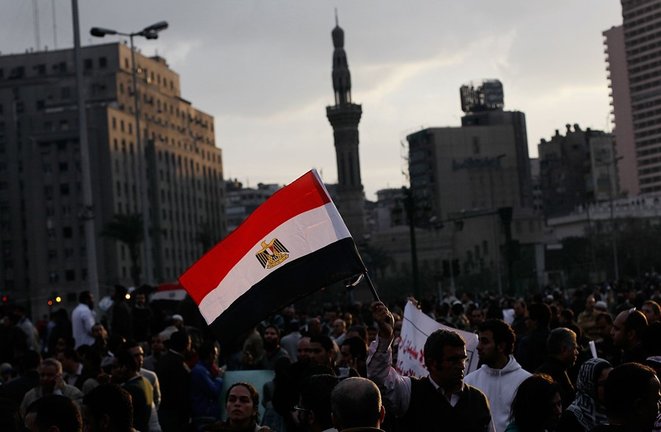 Archivo - Un hombre sostiene una bandera egipcia mientras el sol se pone en una protesta masiva antigubernamental en la Plaza Tahrir el 30 de enero de 2011 en El Cairo.