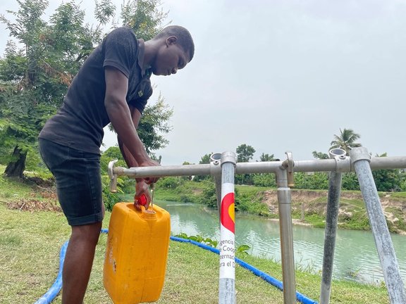 Un hombre en un punto de aprovisionamiento de agua instalado con ayuda de AECID en Haití
