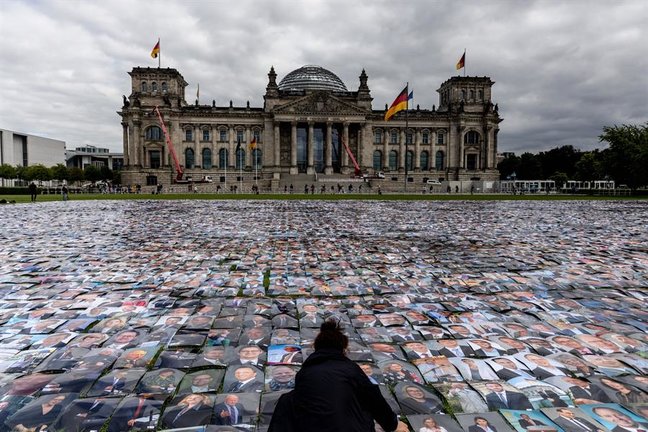 Un activista del grupo de derechos humanos Unverhandelbar (no negociable) coloca fotos de políticos alemanes frente al edificio del Reichstag, sede del Parlamento alemán, durante la protesta contra las violaciones de los derechos humanos en las fronteras exteriores de Europa en Berlín, Alemania, el 16 de septiembre de 2021. (Protestas, Alemania) EFE/EPA/FILIP SINGER