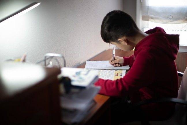 Archivo - Un niño realiza sus deberes en su habitación.