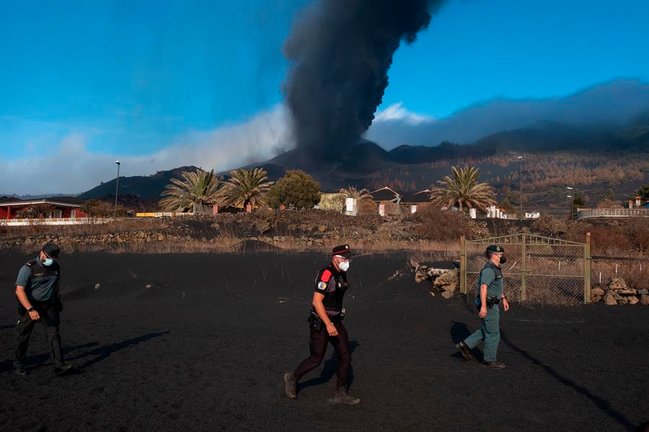 Un agente de la Policía Canarias y dos de la Guardia Civil patrullan este lunes por el barrio de Las Manchas, en La Palma, dentro de la zona evacuada por su proximidad al volcán y a sus emisiones de lava, ceniza y piroclastos. EFE/Carlos de Saá