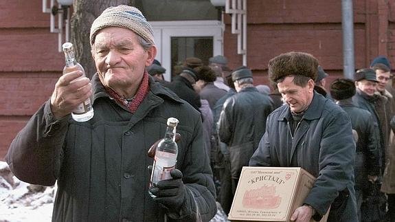 Un anciano sale de una destilería de Rusia con dos botellas de vodka. / EFE