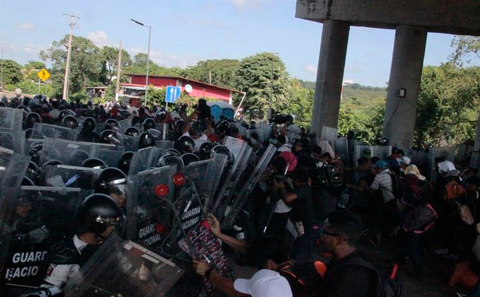 Miembros de la Guardia Nacional chocan con un grupo de migrantes al intentar detener su caravana en el tramo carretero Tapachula- Viva México, hoy, en el estado de Chiapas (México). EFE/ Juan Manuel Blanco