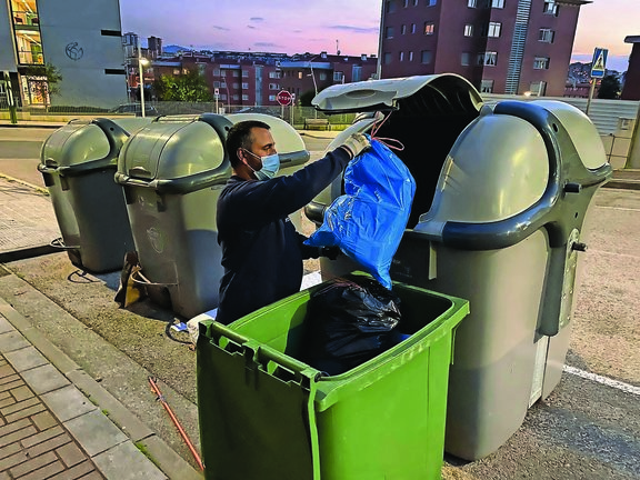 Una persona tira la basura en un día que cambia tras 28 años el servicios de concesionaria en Santander. / HARDY