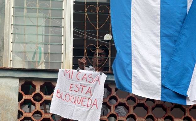 Yunior García en su piso con un cartel que dice "Mi casa está bloqueada".AFP