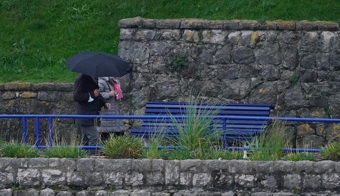 Dos personas con paraguas por las inmediaciones de la playa de El Camello en Santander. / Hardy