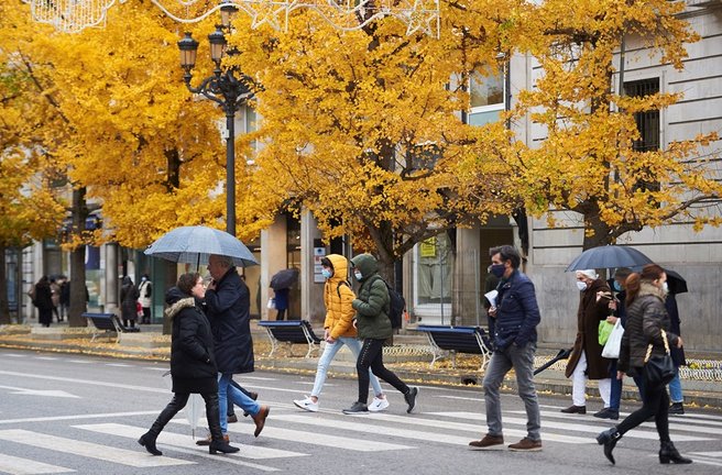 Varias personas con paraguas cruzan un paso para peatones en Santander.- Archivo