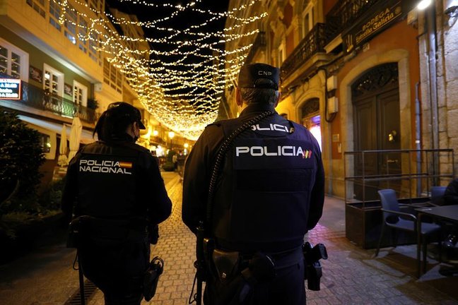 Dos agentes de la Policía Nacional patrullan por una céntrica calle de A Coruña, este martes. Galicia ha anunciado la puesta en marcha de un "toque de no queda", con la prohibición de estar por la calle entre las 2 y las 6 de la madrugada, excepto para desplazamientos individuales o de la misma unidad familiar, y restringe el horario de la hostelería a las 12 horas y del ocio nocturno a las 2 con carácter general. EFE/ Cabalar