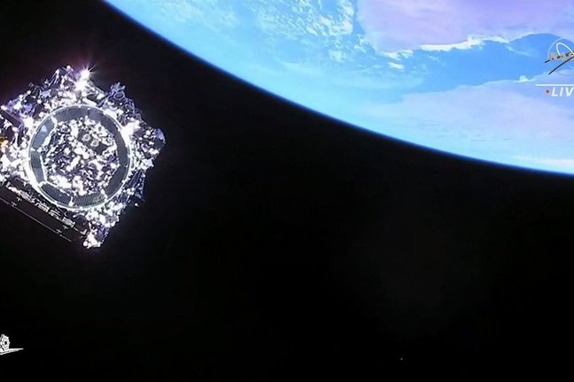 Imagen de televisión de la Nasa que muestra al telescopio James Webb (abajo a la izquierda) tras separarse del cohete Ariane 5. Foto: AFP