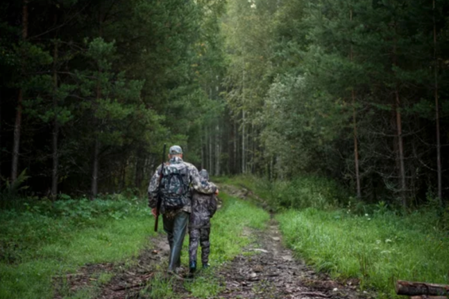 Un hombre en el bosque de caza con su hijo.