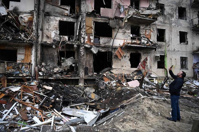 Un ciudadano ucraniano toma fotografías de cómo quedó unas edificaciones ubicadas en la avenida Koshytsa, suburbio de Kiev, luego de los bombardeos rusos. Foto: afp
