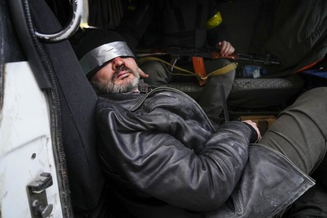 Un presunto agente ruso es mantenido bajo vigilancia armada mientras es escoltado con los ojos vendados en Kiev.  / AP