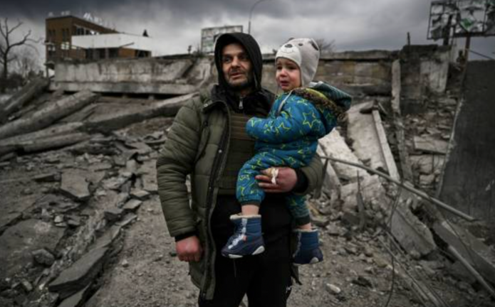 Un hombre sostiene a un niño mientras huye de la ciudad de Irpin, al oeste de Kiev, el 7 de marzo de 2022. - Las fuerzas rusas bombardearon ciudades ucranianas desde el aire, la tierra y el mar el lunes, con advertencias de que se estaban preparando para un asalto a la capital, Kiev, mientras los civiles aterrorizados no lograron, por segundo día, escapar de la sitiada Mariupol. (Foto de ARIS MESSINIS / AFP)