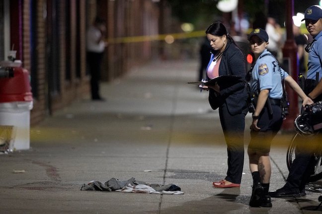 El policía de Filadelfia D. F. Pace examina las pruebas en el lugar de un tiroteo en South Street y sus alrededores que dejó 3 muertos y 11 heridos el 4 de junio de 2022.