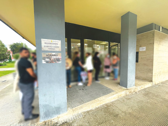 Gente esperando en la puerta de las oficinas municipales del Registro y Padrón del Ayuntamiento de Torrelavega. Parte de la imagen se ha distorsionado para preservar la intimidad de las personas. / ALERTA