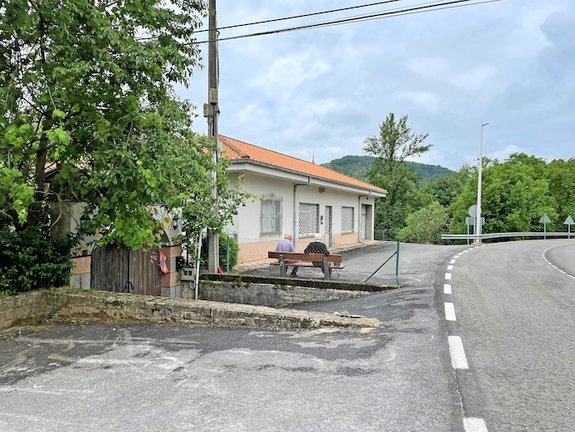 Dos personas de avanzada edad frente al consultorio médico de Anievas, al otro lado de la carretera. / ALERTA