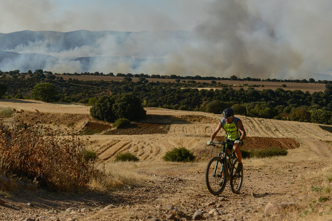 Un ciclista circula cerca del incendio de Valdepeñas de la Sierra (Guadalajara)./ Nacho Izquierdo
