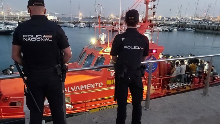Agentes de la Policía Nacional junto a una embarcación de salvamento que rescató a inmigrantes. /E.P.