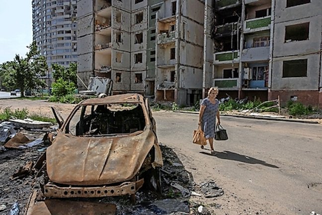 Una mujer pasa este lunes junto a un coche quemado y un edificio residencial da??ado en Chernihiv, en el norte de Ucrania. EFE/EPA/ROMAN PILIPEY

