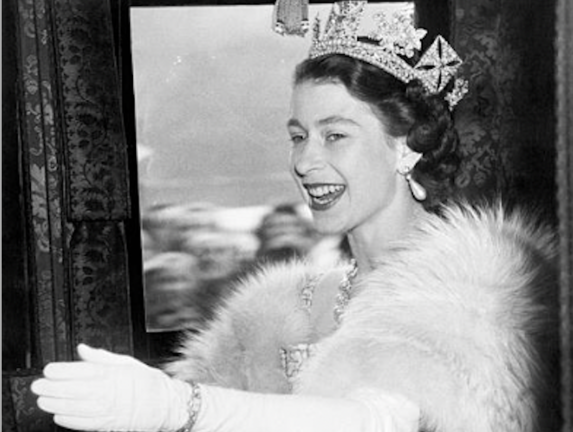 La reina Isabel II, de 26 años de edad, está radiantemente feliz aquí mientras saluda y sonríe en reconocimiento de los vítores de la multitud mientras se dirigía en el autocar de Estado a la Cámara de los Lores.