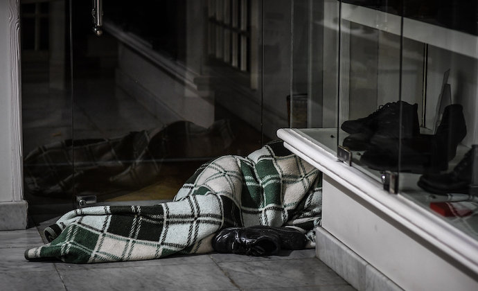 Una persona duerme en la entrada de una tienda de ropa de Santander. / ALERTA