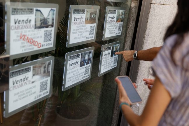 Unas personas se paran delante del escaparate de una inmobiliaria que publicita los inmuebles que gestiona en Madrid FOTO: MARISCAL EFE