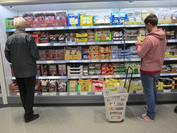 Dos hombres ante el expositor de una supermercado. / E.P.