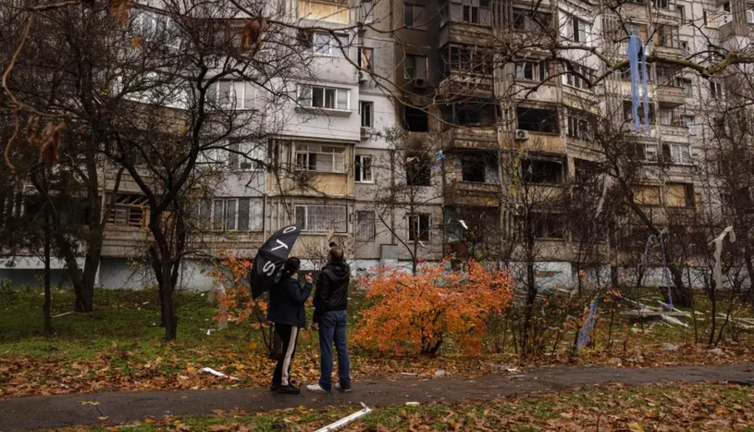 Ucranianos delante de un edificio dañado por bombas rusas en Jersón. EFE/EPA/ROMAN PILIPEY
