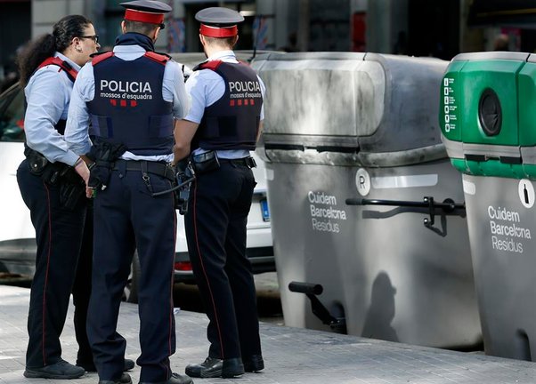 Tres mossos permanecen junto al contenedor donde esta mañana se ha encontrado el cadáver mutilado de una persona dentro de una maleta en el barrio de L'Eixample de Barcelona. EFE/Andreu Dalmau