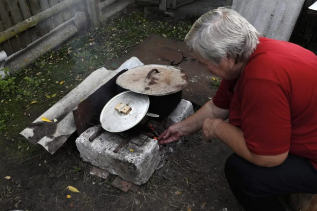 Una mujer prepara la comida en un horno de piedra en una aldea de Ucrania. EFE/EPA