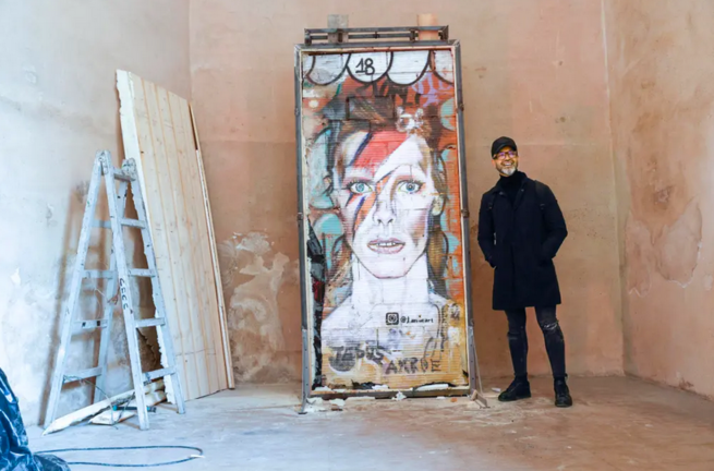 GRAFCVA245. VALENCIA, 12/12/2022.-El artista Jesus Arrúe posa con el el grafiti de David Bowie que dibujó en un muro de la ciudad de Valencia y que ha sido trasladado desde la ubicación callejera en el que fué creado, al museo del Carme, que va a contar desde ahora con esta obra de arte urbano. EFE/ Manuel Bruque