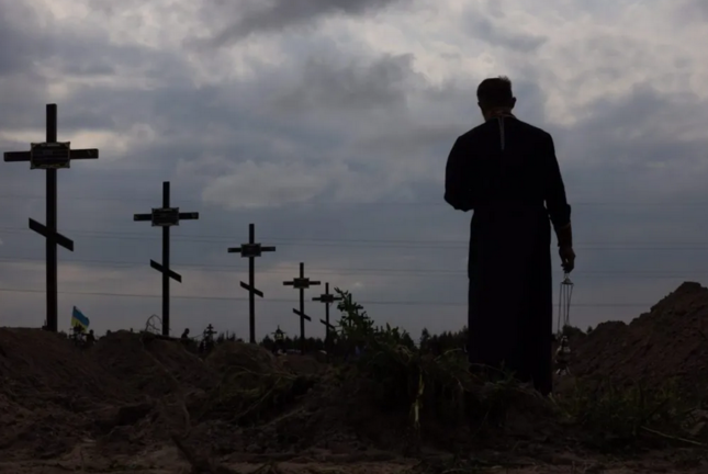 Un sacerdote ortodoxo bendecía los restos de personas no identificadas que fueron asesinadas en el distrito de Bucha, al noroeste de Kiev, el pasado mes de agosto. EFE/EPA/Roman Pilipey