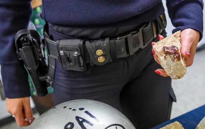 Una agente de la Policía Nacional muestra un piedra usada en un enfrentamiento entre grupos ultras del Sevilla F.C. y del Real Betis Balompié. EFE / Raúl Caro