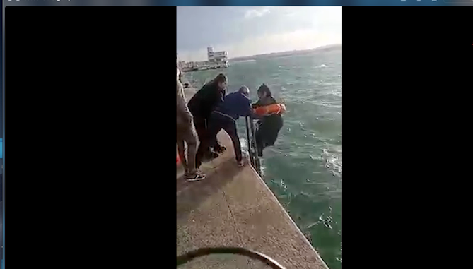 Varias personas ayudan a esta mujer que acabó en el agua por causa del viento sur. / ALERTA