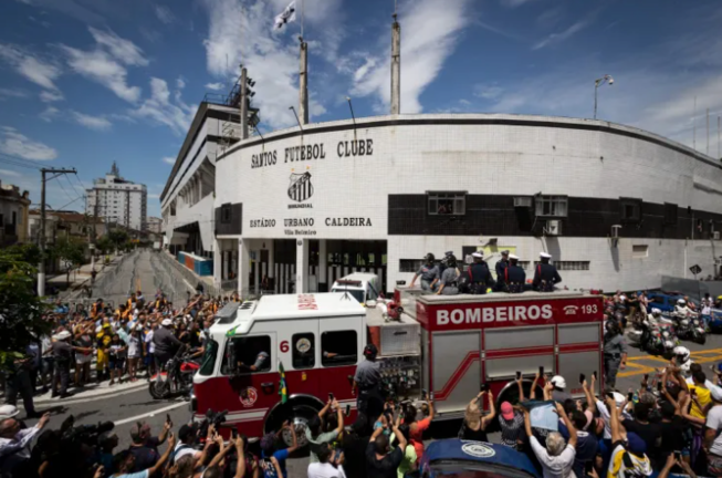 Un camión de bomberos que transporta el féretro con el cuerpo de la leyenda del fútbol Edson Arantes do Nascimento 'Pelé encabeza hoy el cortejo fúnebre que recorrerá algunas calles de la ciudad de Santos (Brasil). EFE/Isaac Fontana