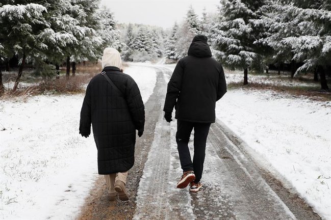 - Dos personas pasean por un paisaje nevado en O'Cebreiro (Lugo) este sábado. La llegada de un frente frío ha dejado nieve en cotas superiores a los 800 metros. EFE/ Eliseo Trigo
