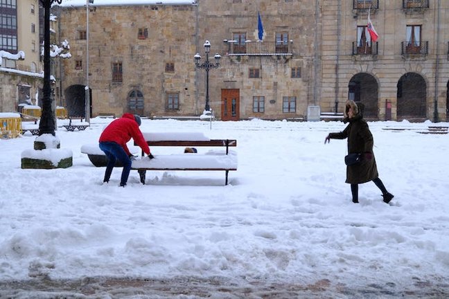 Varias personas juegan frente al Ayuntamiento de Reinosa, en las nevada de la pasada semana. / Eugenio Martínez