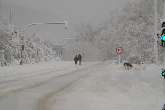 Dos personas transitan por una carretera nevada en la localidad de Campoo de Suso. / Eugenio Martínez