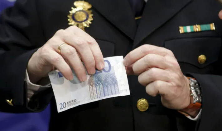 Un agente de Policía con un billete falso de 20 euros. EFE / Ángel Díaz