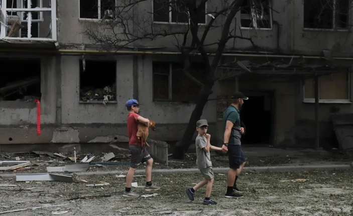 Varias personas en una calle de Bajmut, en la región de Donetsk, en la que se aprecian los efectos de los bombardeos rusos. EFE